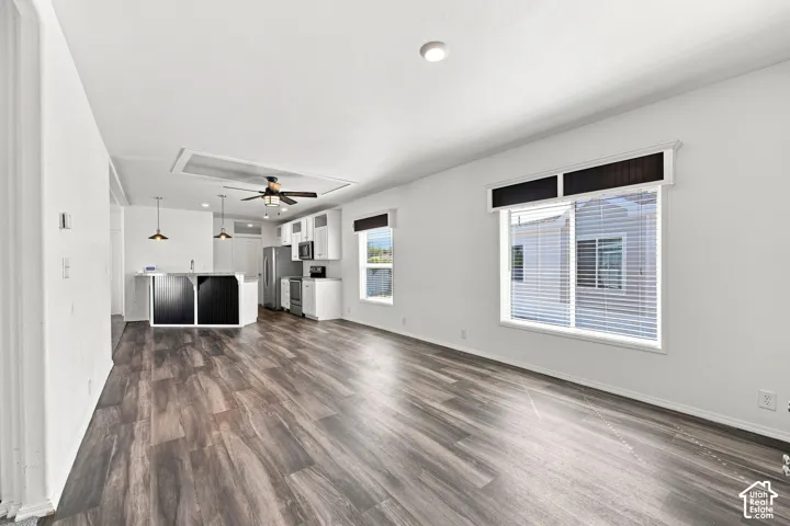 Spacious interior with wood-finish flooring, white walls, and a ceiling fan