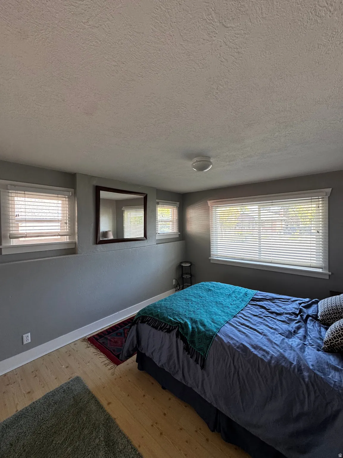 Room featuring light wood-finish flooring, multiple windows with blinds, and a built-in overhead light fixture
