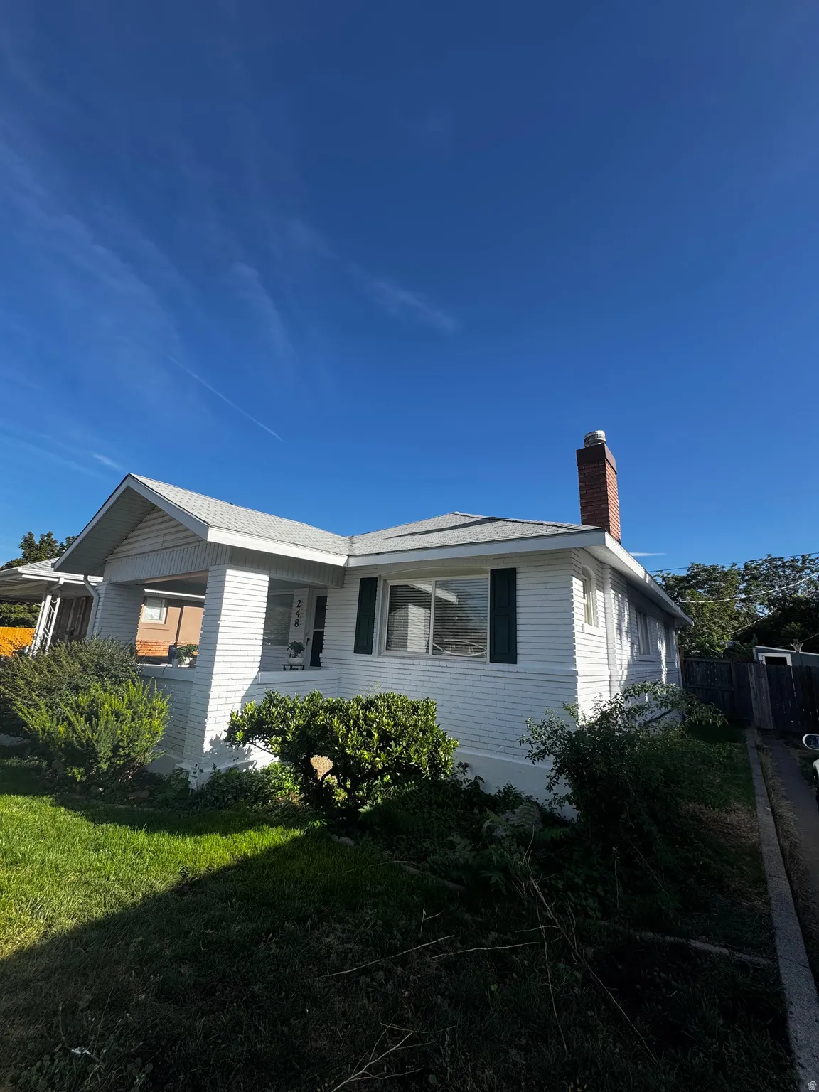 White siding exterior with a brick chimney and a covered porch