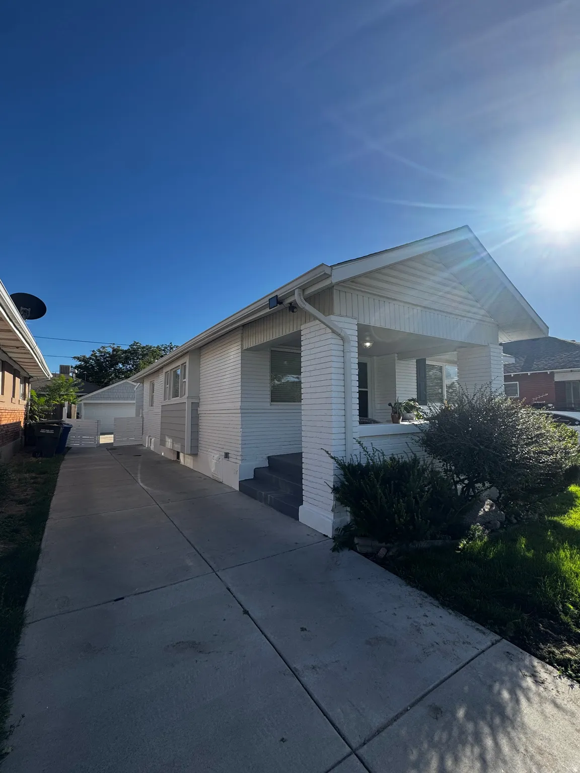 Front facade with white siding and brick accents, covered porch entrance, and a concrete driveway
