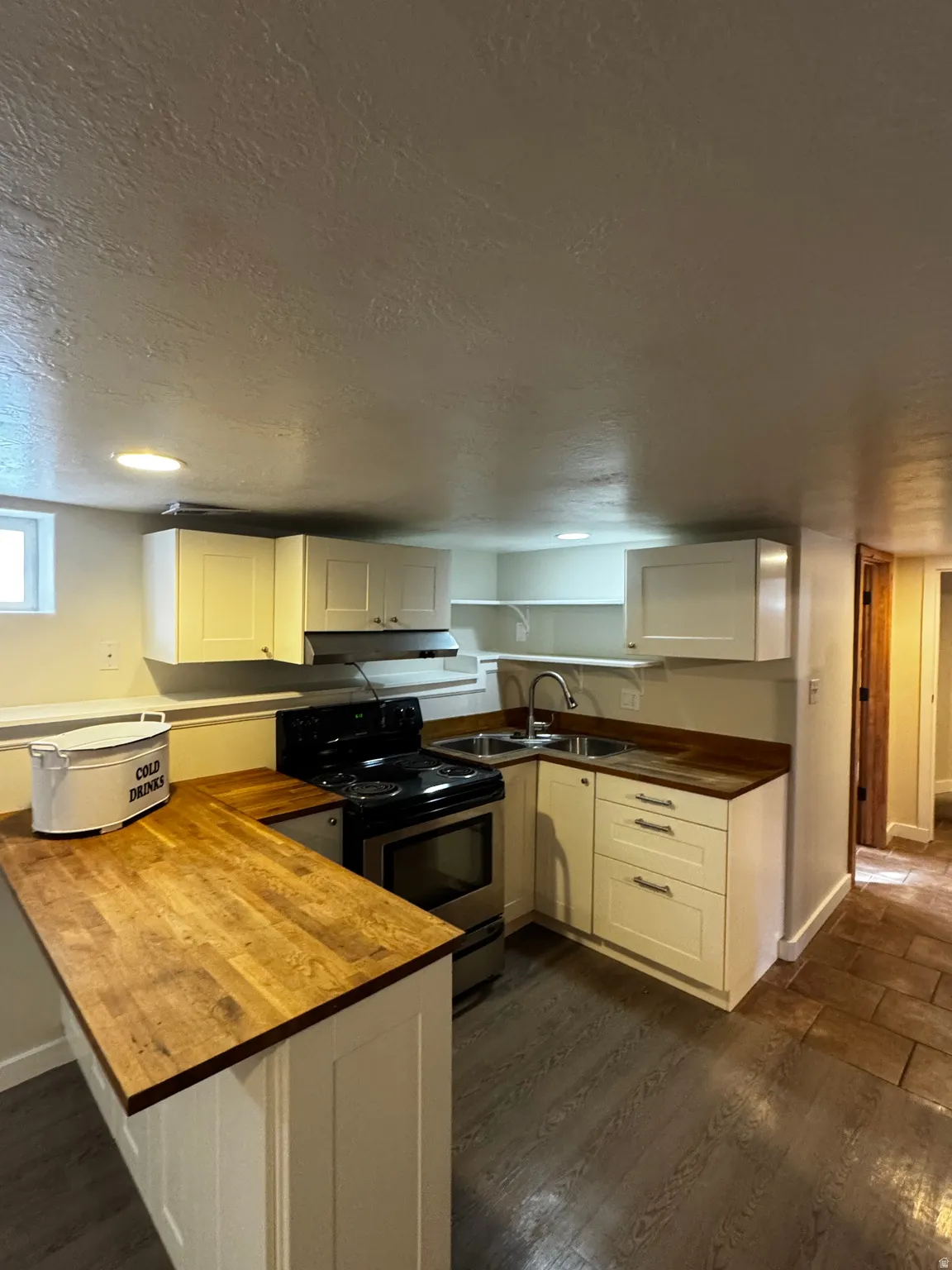 Compact kitchen featuring wood-finish countertops, white cabinetry, and stainless steel appliances