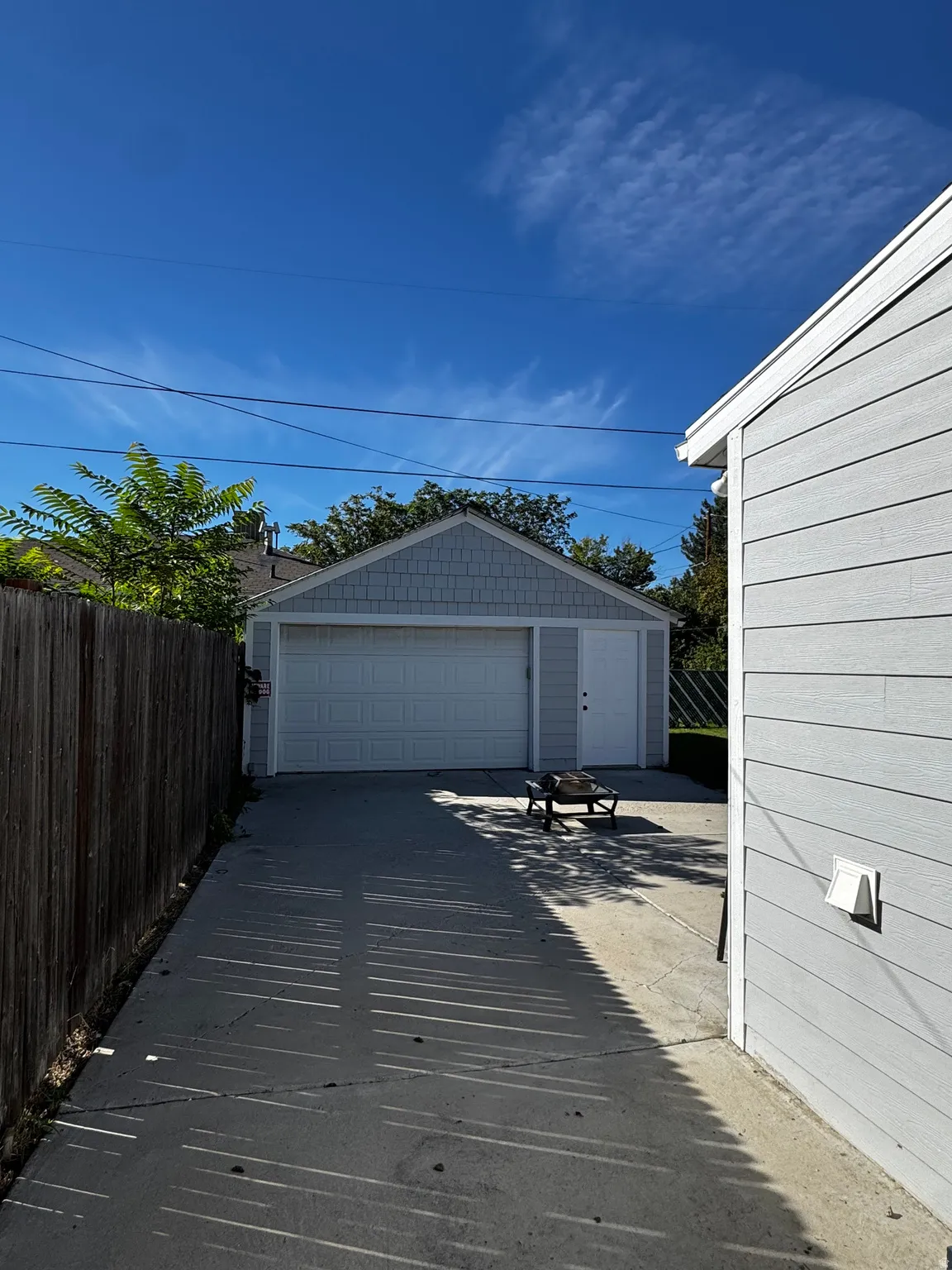 Detached garage with a paneled door, horizontal siding, and a side entrance