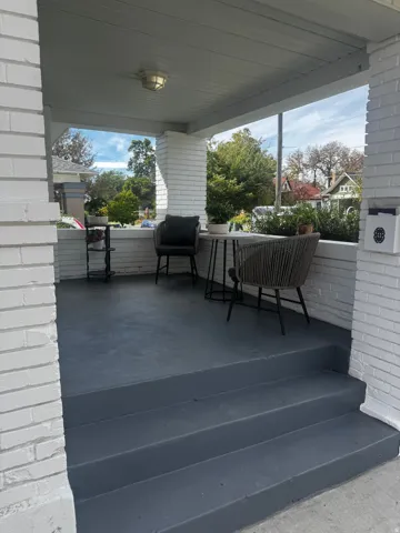 Porch entrance with painted brick columns, a flat ceiling with an attached light fixture, a low brick half-wall, and painted steps
