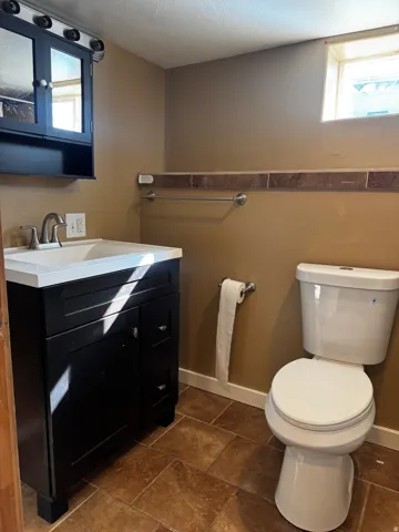 Black vanity with white countertop, chrome faucet, and tiled flooring