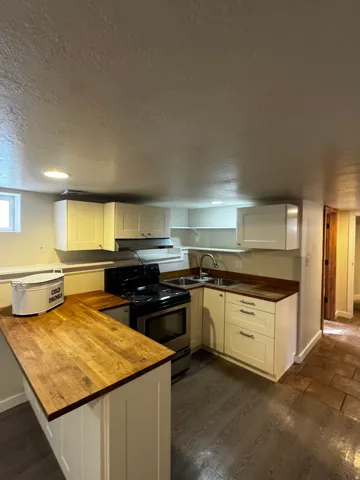 Compact kitchen featuring wood-finish countertops, white cabinetry, and stainless steel appliances
