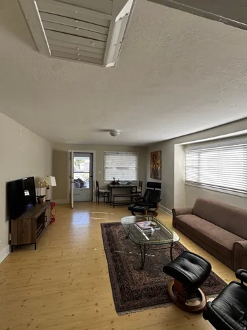 Wood-finish flooring throughout, recessed lighting, and a white ceiling with an attic access panel
