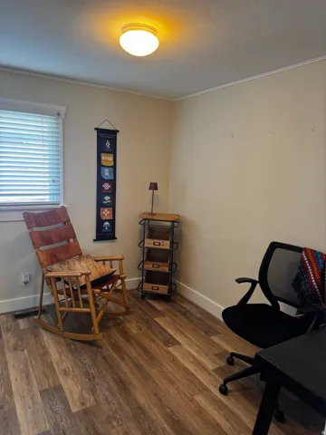 Wood-finish flooring, white trim, and a flush-mount ceiling light