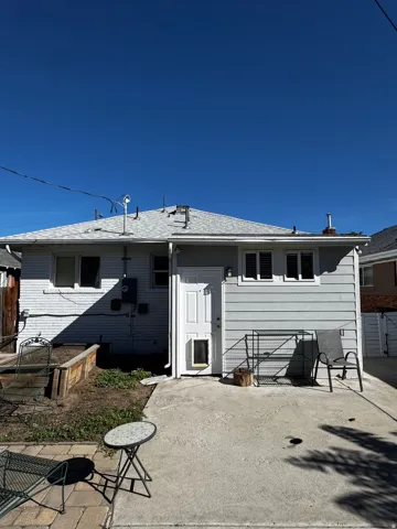 Rear exterior featuring light gray horizontal siding and a white entry door