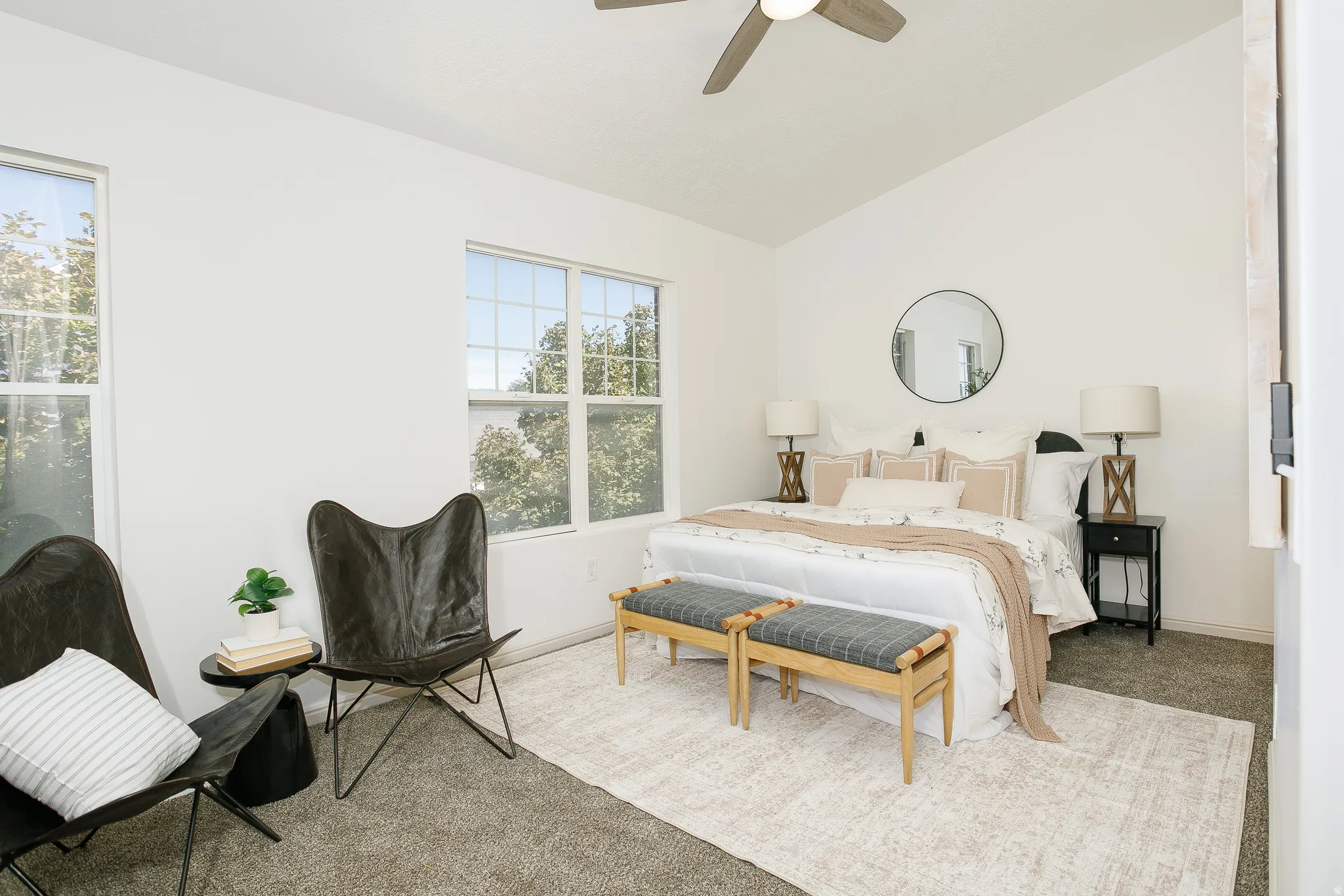 Vaulted ceiling with a ceiling fan, white walls, multiple windows, and carpet flooring