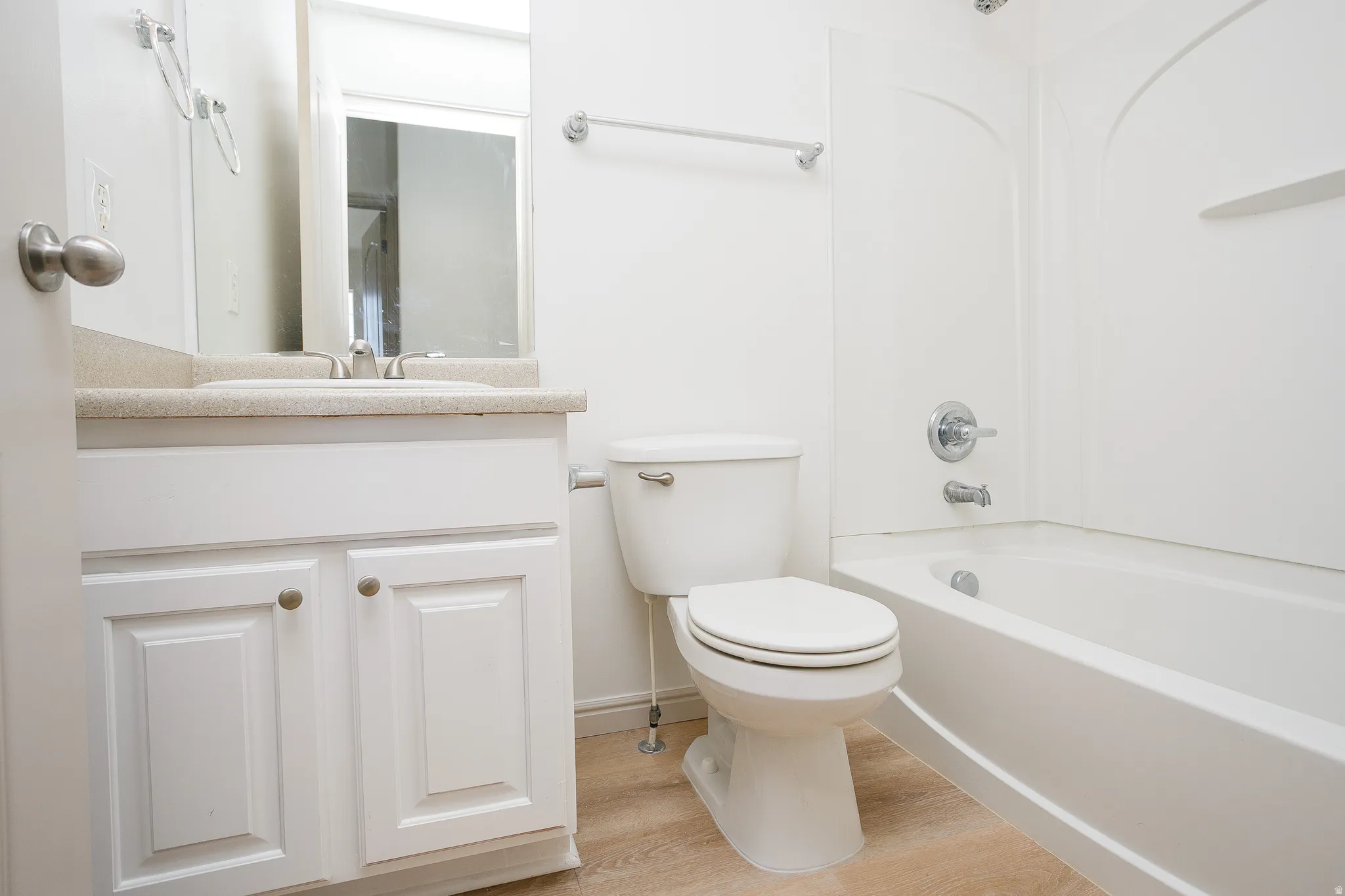 White vanity with shaker-style cabinet doors, single basin sink, and light-toned countertop
