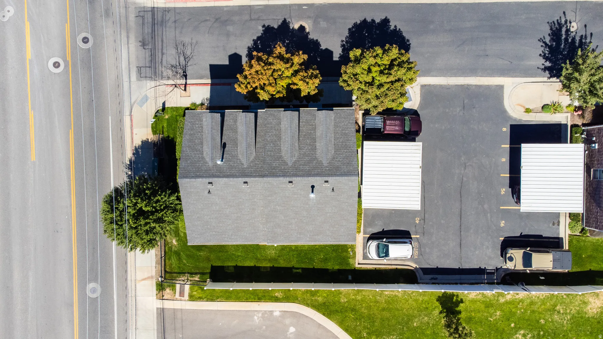 Asphalt shingle roofing over a multi-unit structure, featuring mature trees and a manicured lawn
