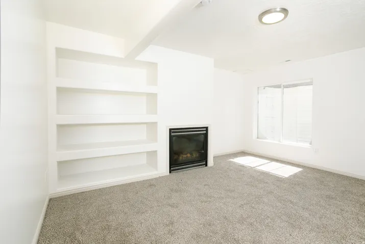 Built-in shelving, integrated fireplace, wall-to-wall carpeting, and recessed lighting