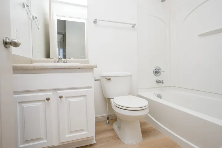 White vanity with shaker-style cabinet doors, single basin sink, and light-toned countertop