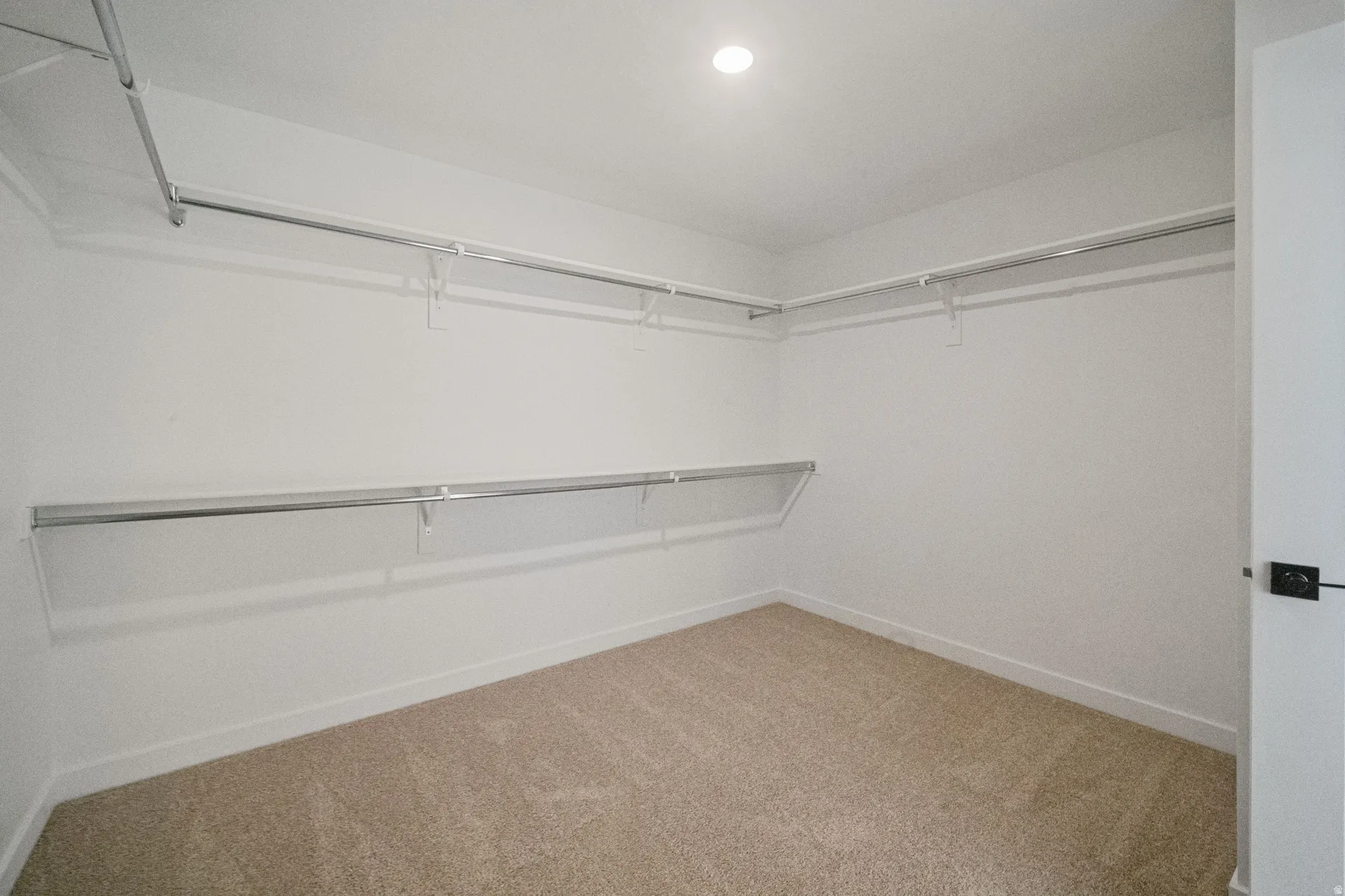 Recessed ceiling lighting, wall-mounted shelving, and metal hanging rods