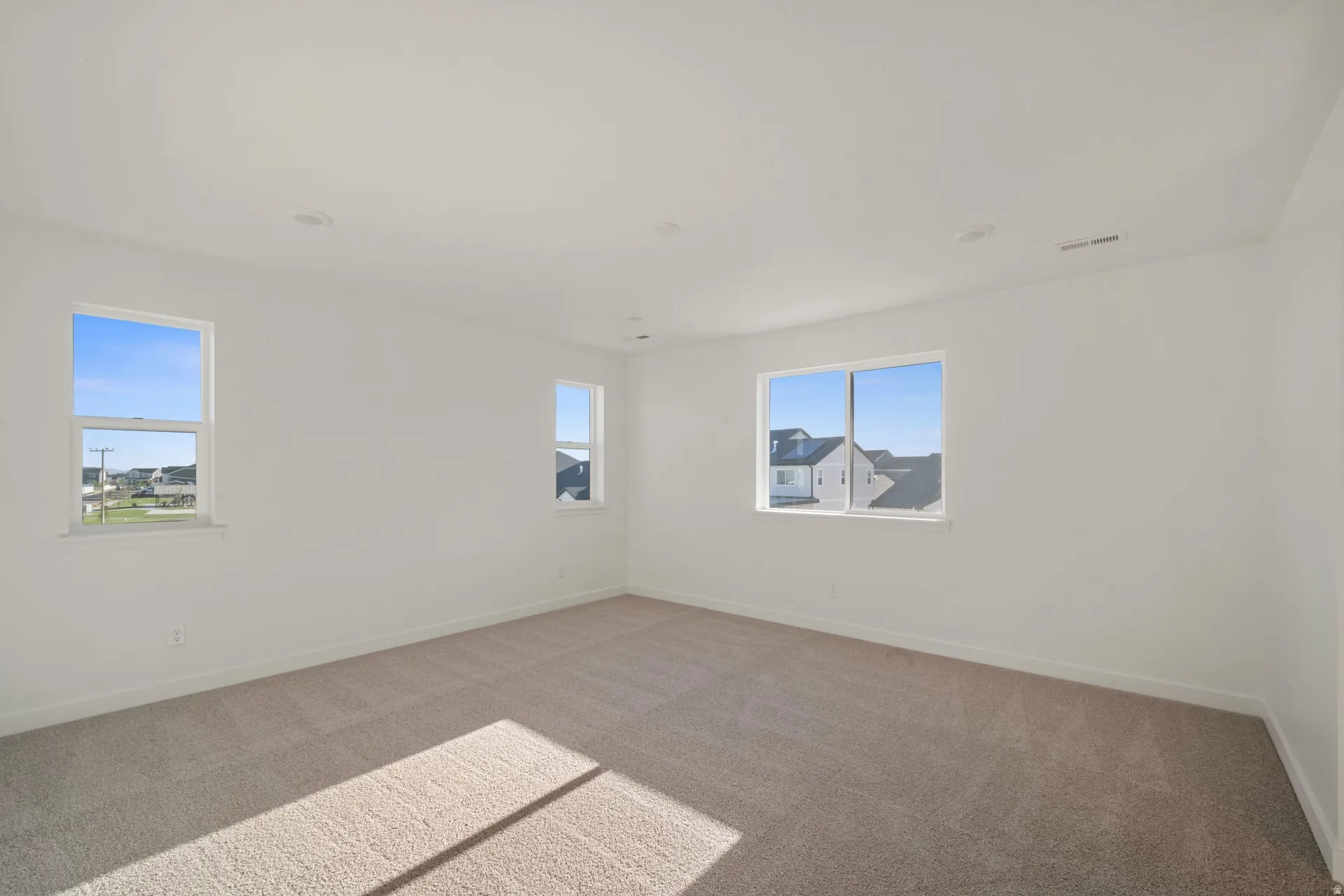Neutral-toned carpeting, white walls, multiple windows, and recessed lighting