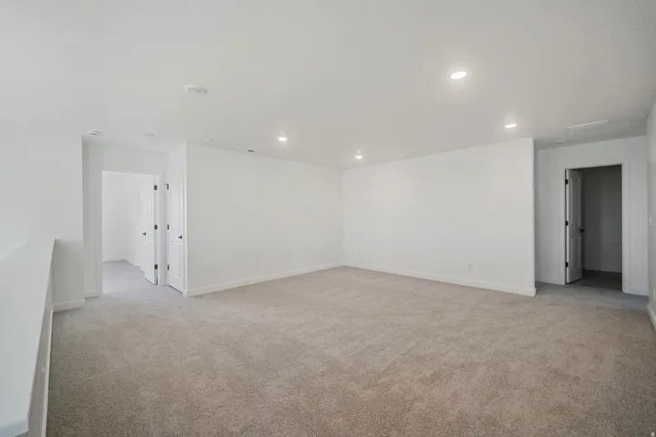 Spacious room with light-toned carpeting and recessed lighting