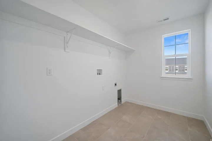 Neutral tile flooring, built-in shelving, white walls, and a single window