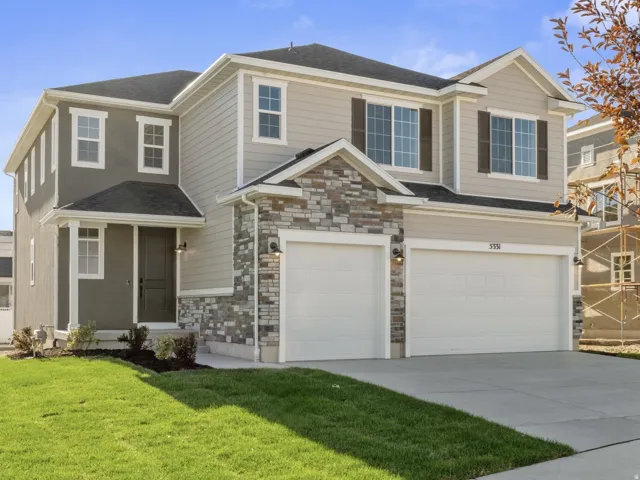 Two-story residence featuring a partial stone facade, dual garage doors, and a covered entry