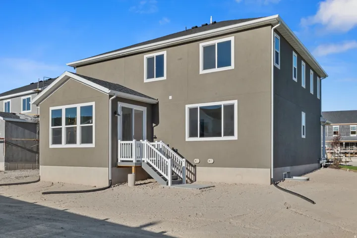 Stucco exterior with white trim, multiple windows, and a sliding glass door leading to exterior stairs