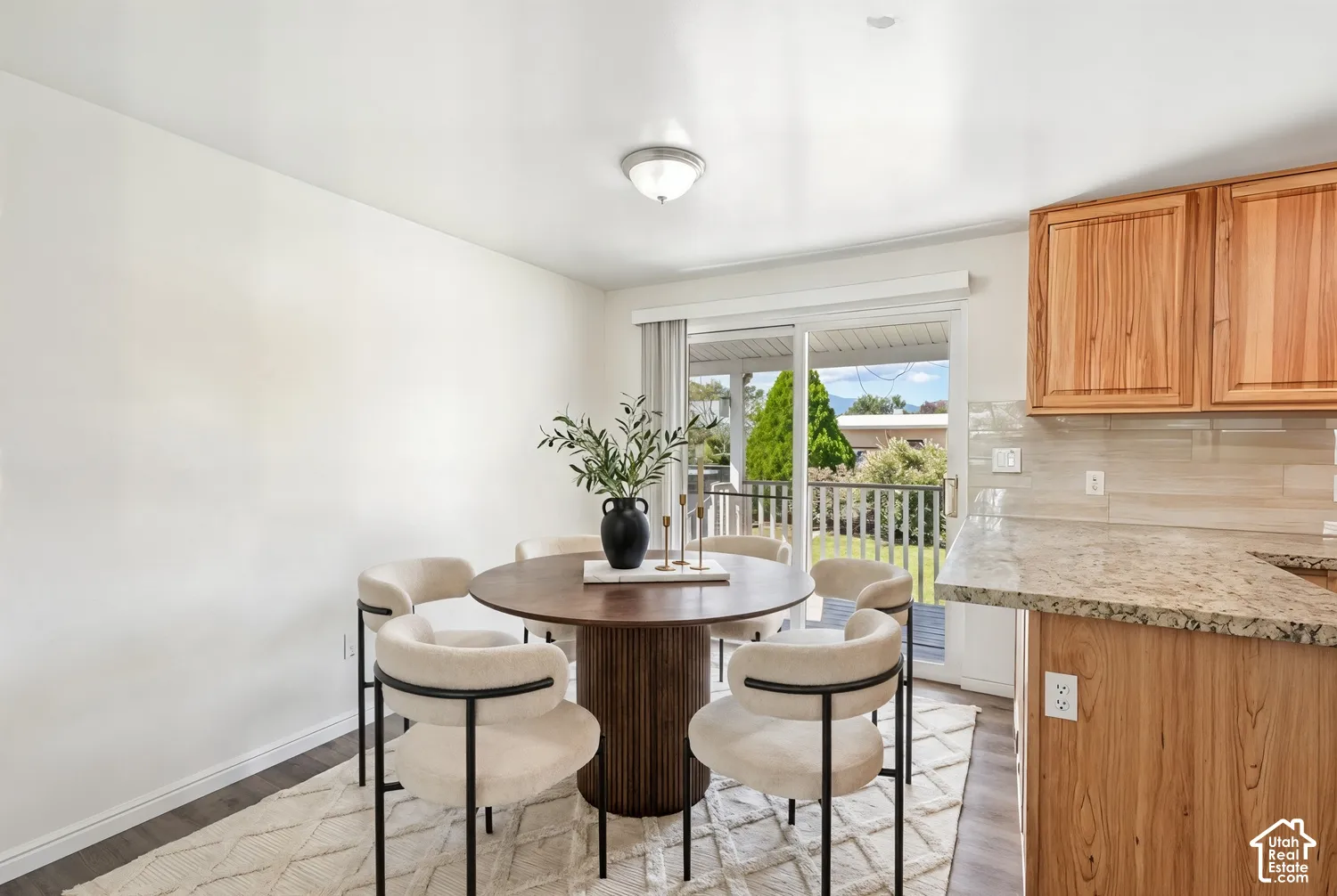Hardwood cabinetry with stone countertops, tile backsplash, and wood-finish flooring