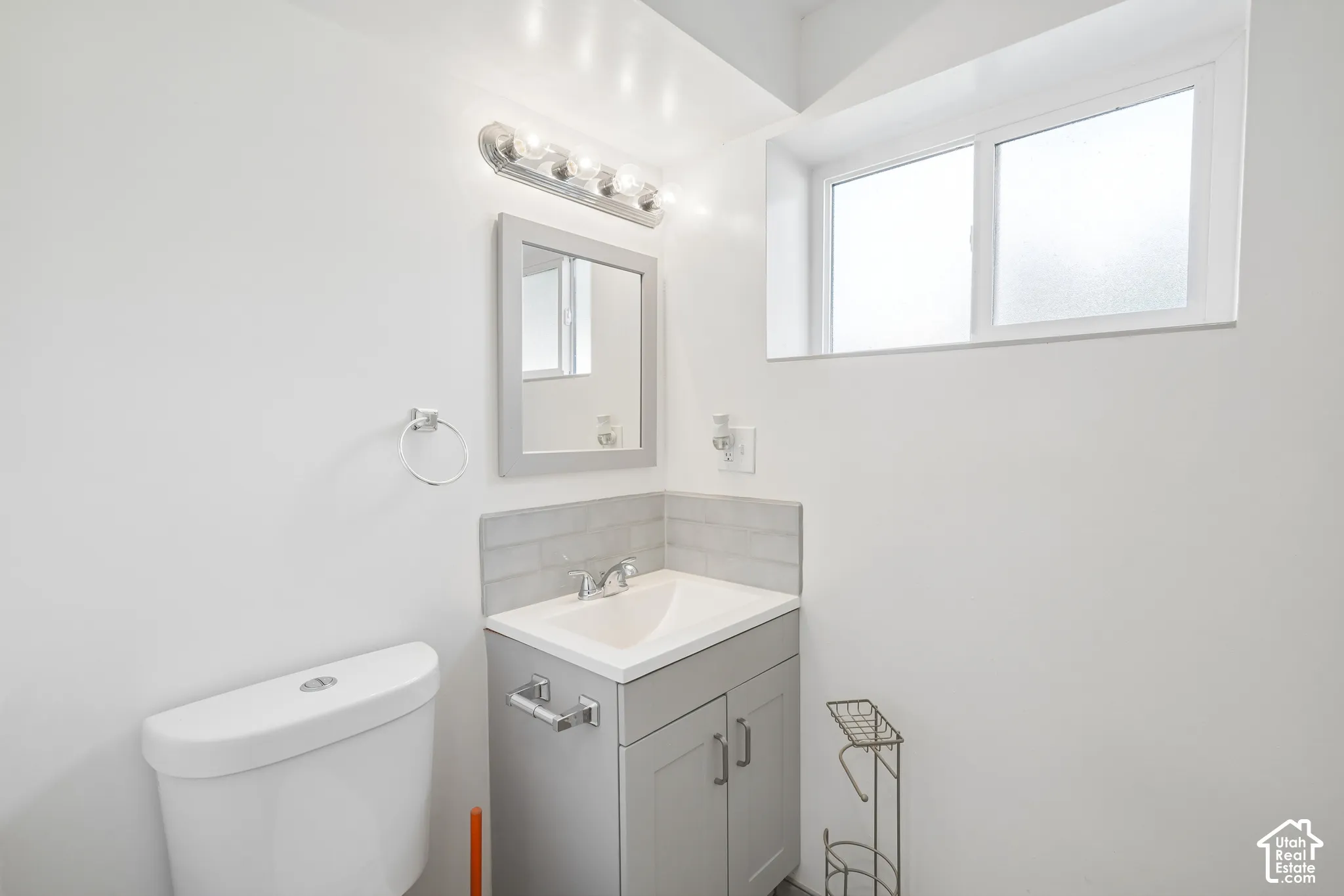 White vanity with a single basin sink, chrome faucet, and gray cabinetry