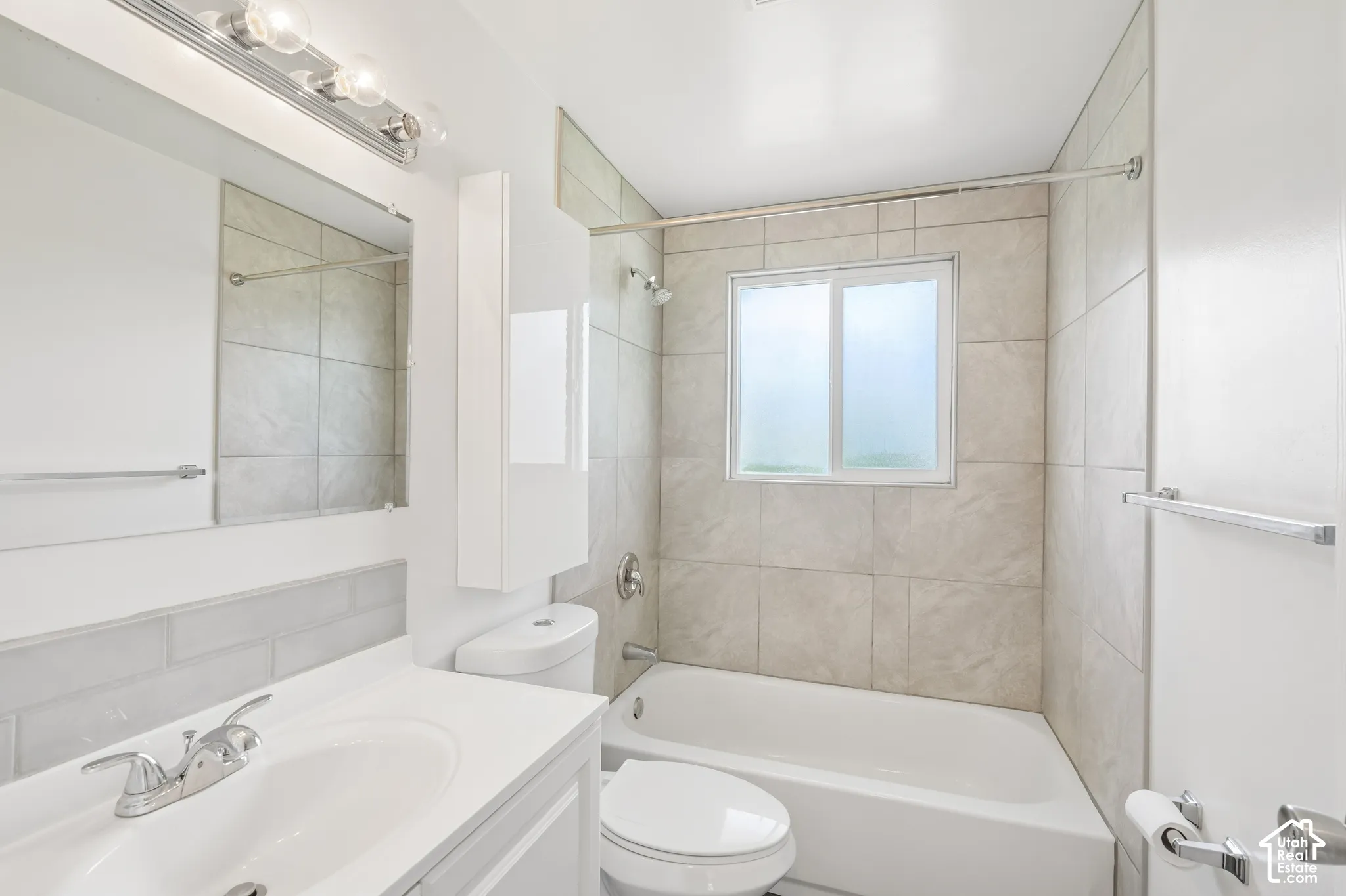 Bathroom with a single vanity, undermount sink, chrome faucet, and subway tile backsplash