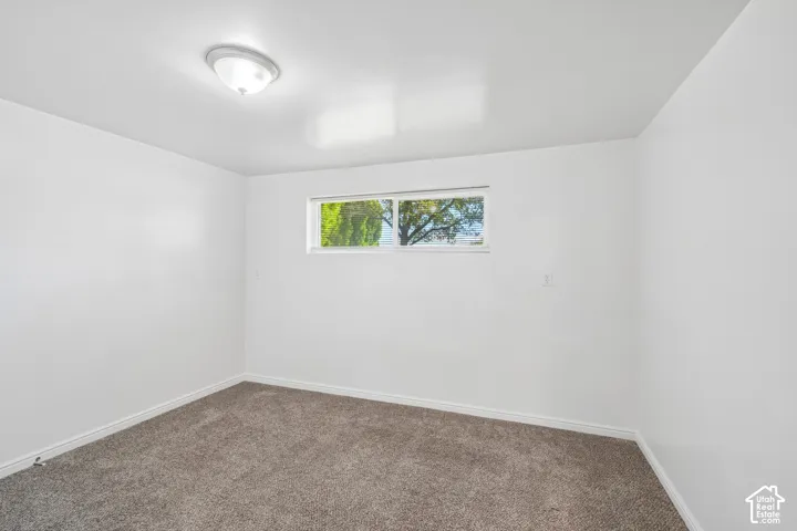 Recessed window, white walls, flush mount ceiling light, and textured carpet flooring