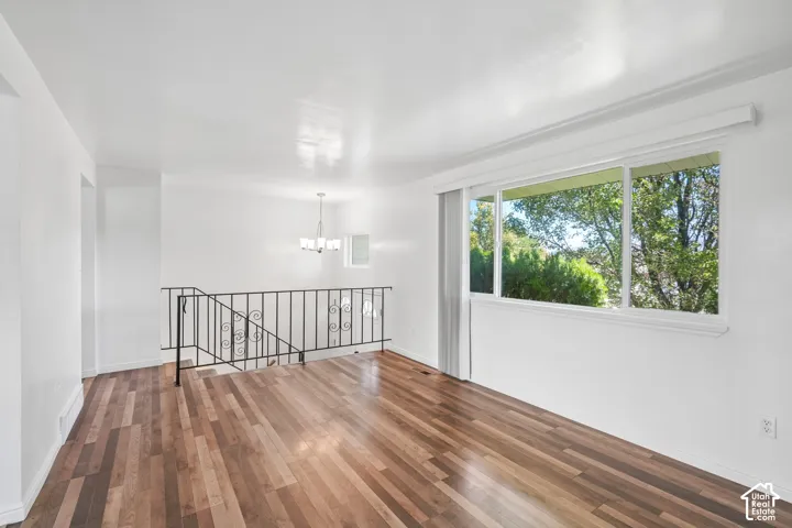 Wood-finish flooring, white walls, large multi-pane window, decorative wrought iron railing, and a contemporary chandelier