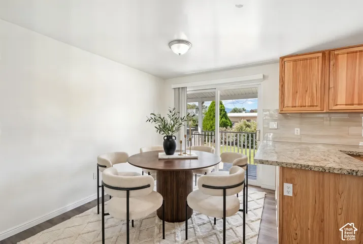 Hardwood cabinetry with stone countertops, tile backsplash, and wood-finish flooring