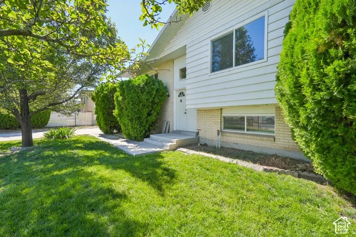 Split-level residence featuring white siding, a light brick foundation, and a concrete entry path with steps