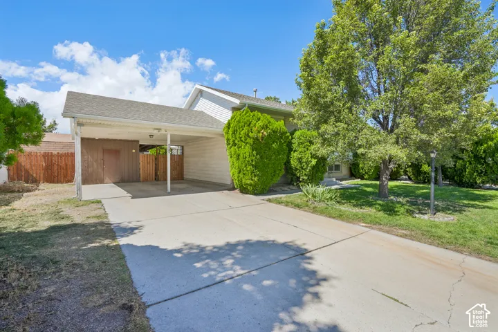 Carport with a concrete driveway and an adjacent wooden fence