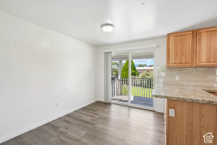 Wood-finish flooring, white walls, and a sliding glass door providing access to an outdoor deck