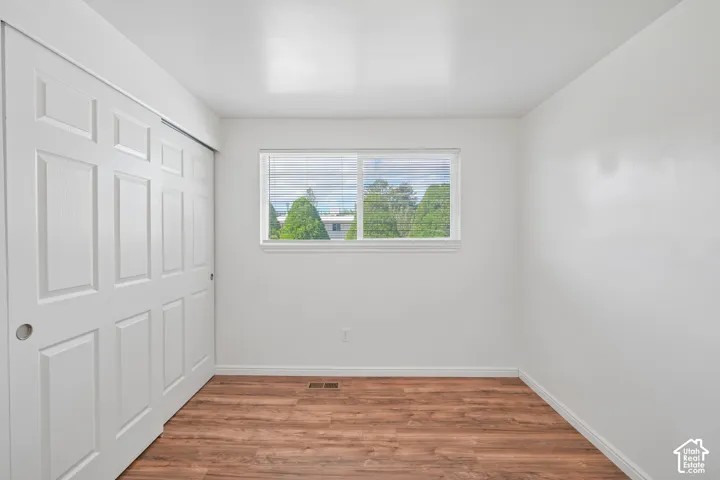 Wood-finish flooring, bright white walls, and a window with blinds