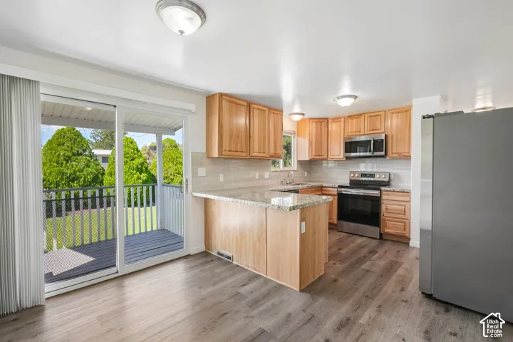 Light wood-finish cabinetry, stainless steel appliances, granite countertops, and wood-finish flooring