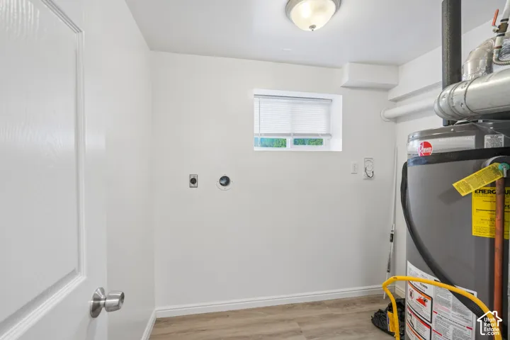 Dedicated utility space featuring a water heater, small window, wood-finish flooring, and a flush-mount ceiling light