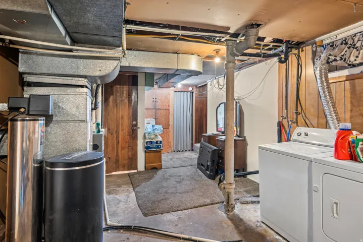Utility area featuring a washer and dryer, exposed ductwork, and a built-in water treatment system