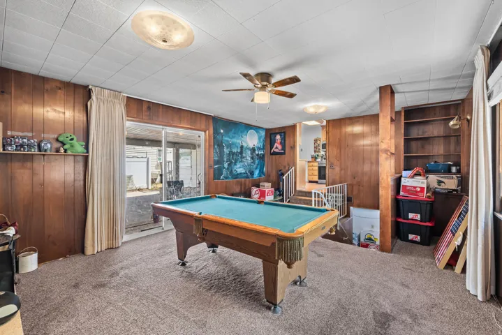 Wood-paneled room featuring a ceiling fan, recessed lighting, and a sliding glass door