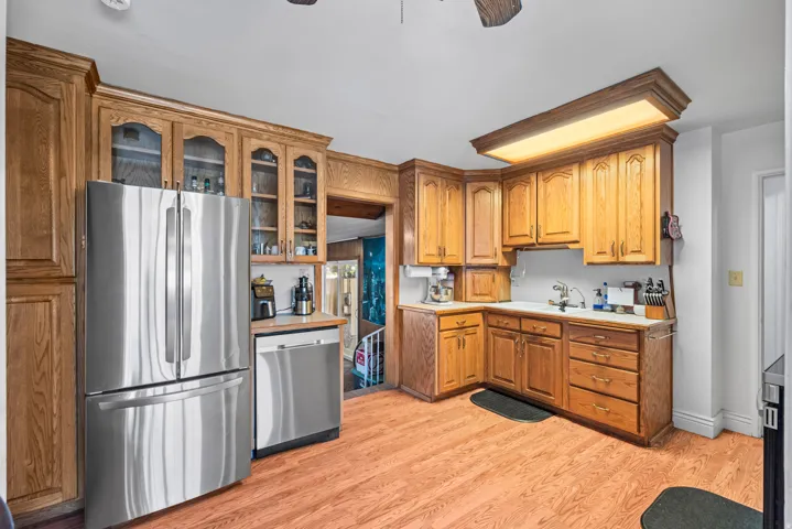 Kitchen featuring wood-finish flooring, wood cabinetry with glass-front accents, and stainless steel appliances