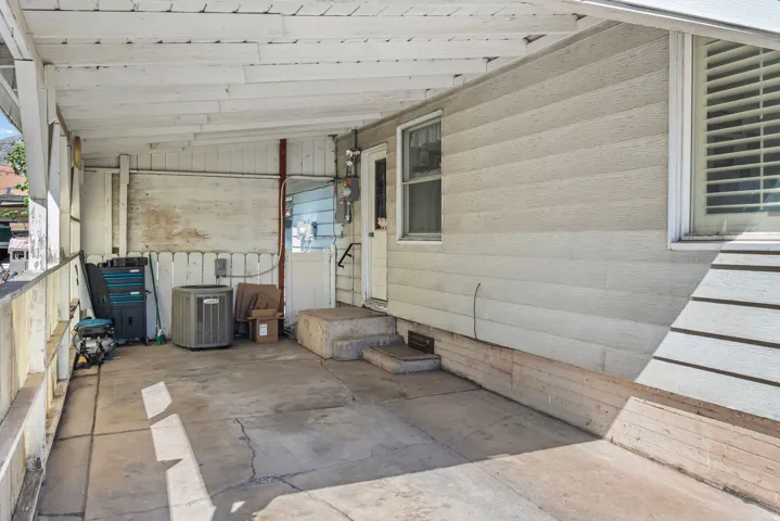 Covered concrete patio with white wood paneling and a white slatted fence