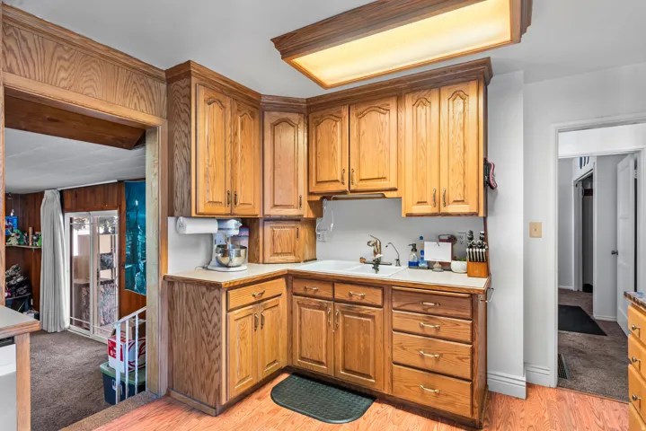 Corner kitchen featuring wood cabinetry, a built-in sink, and light-toned countertops