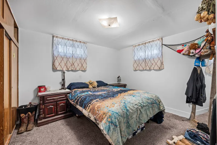 White walls with a ceiling-mounted light fixture, two windows, and wood-finish closet doors