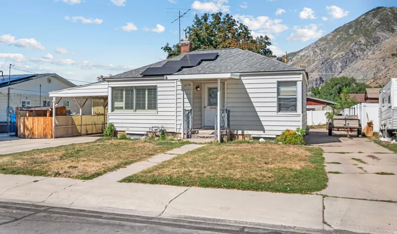 Single-story residence featuring white siding, a covered porch entry, and an asphalt shingle roof with visible solar panels
