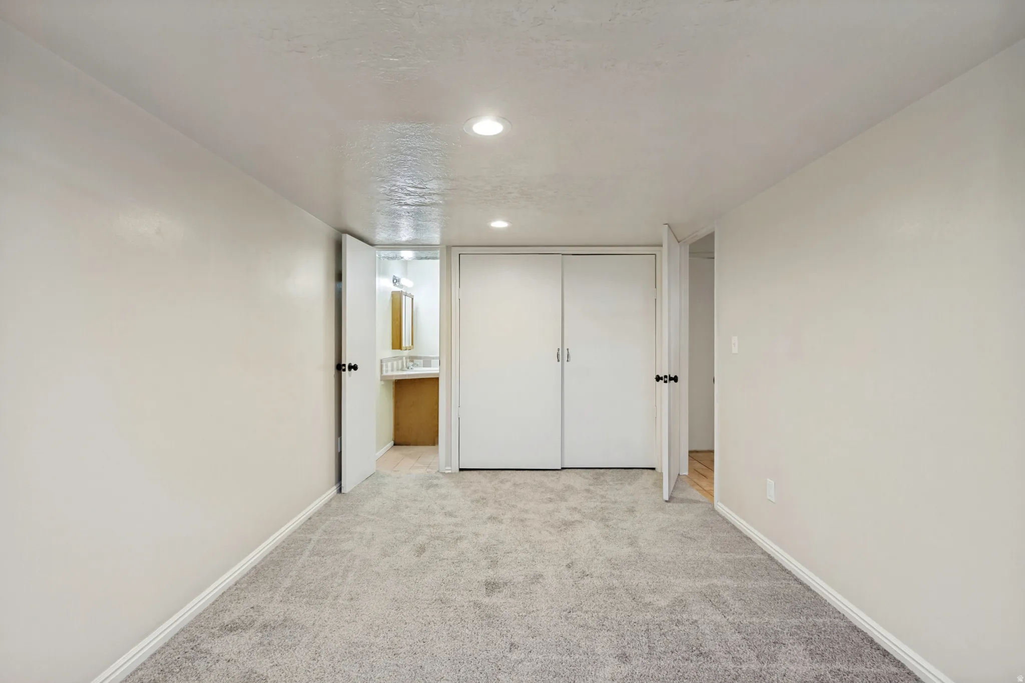 ADU - Recessed lighting, light gray carpet flooring, white walls, and white bi-fold closet doors