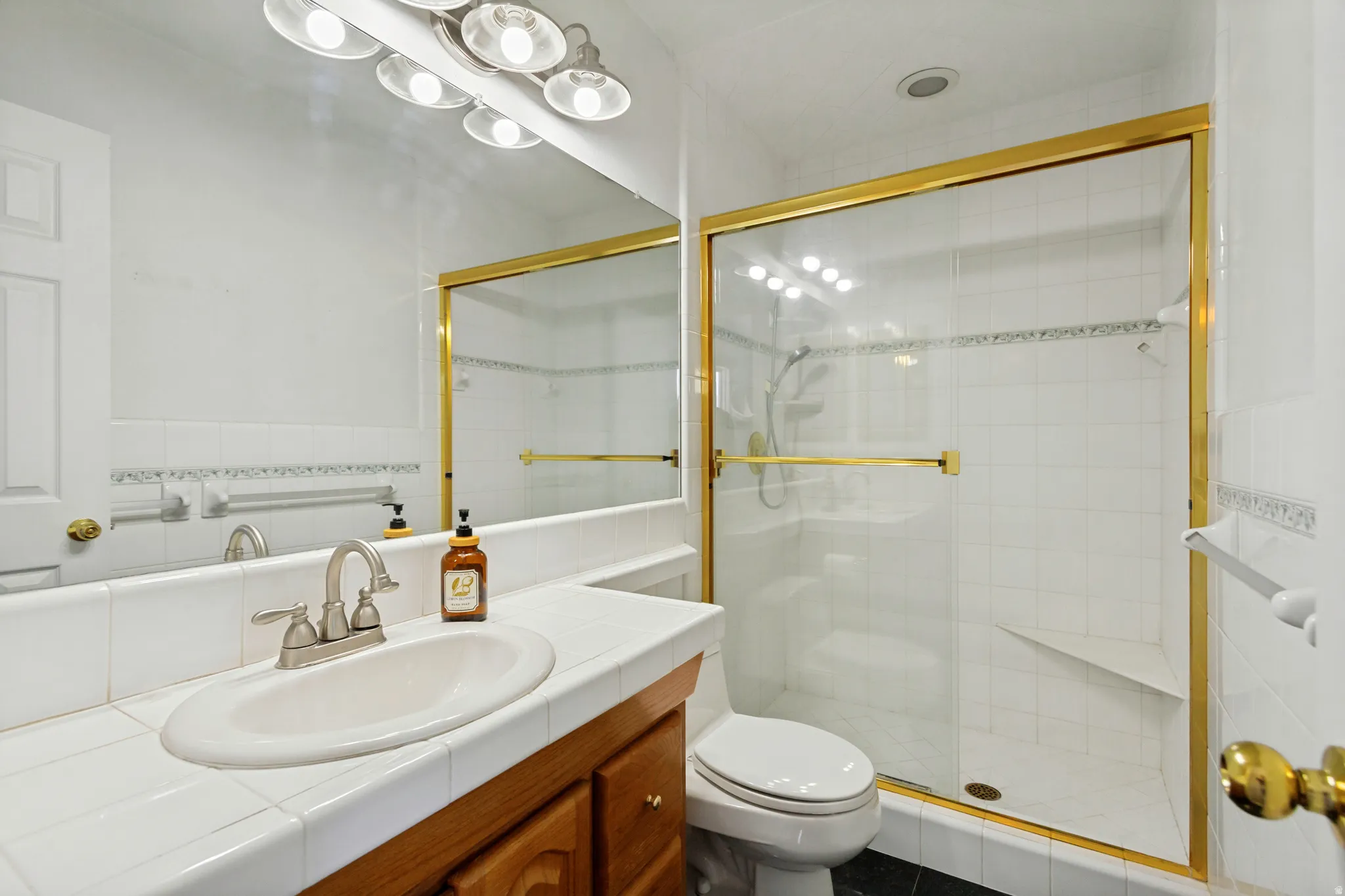 Primary - Vanity with a tiled countertop, undermount sink, and wood-finish cabinetry