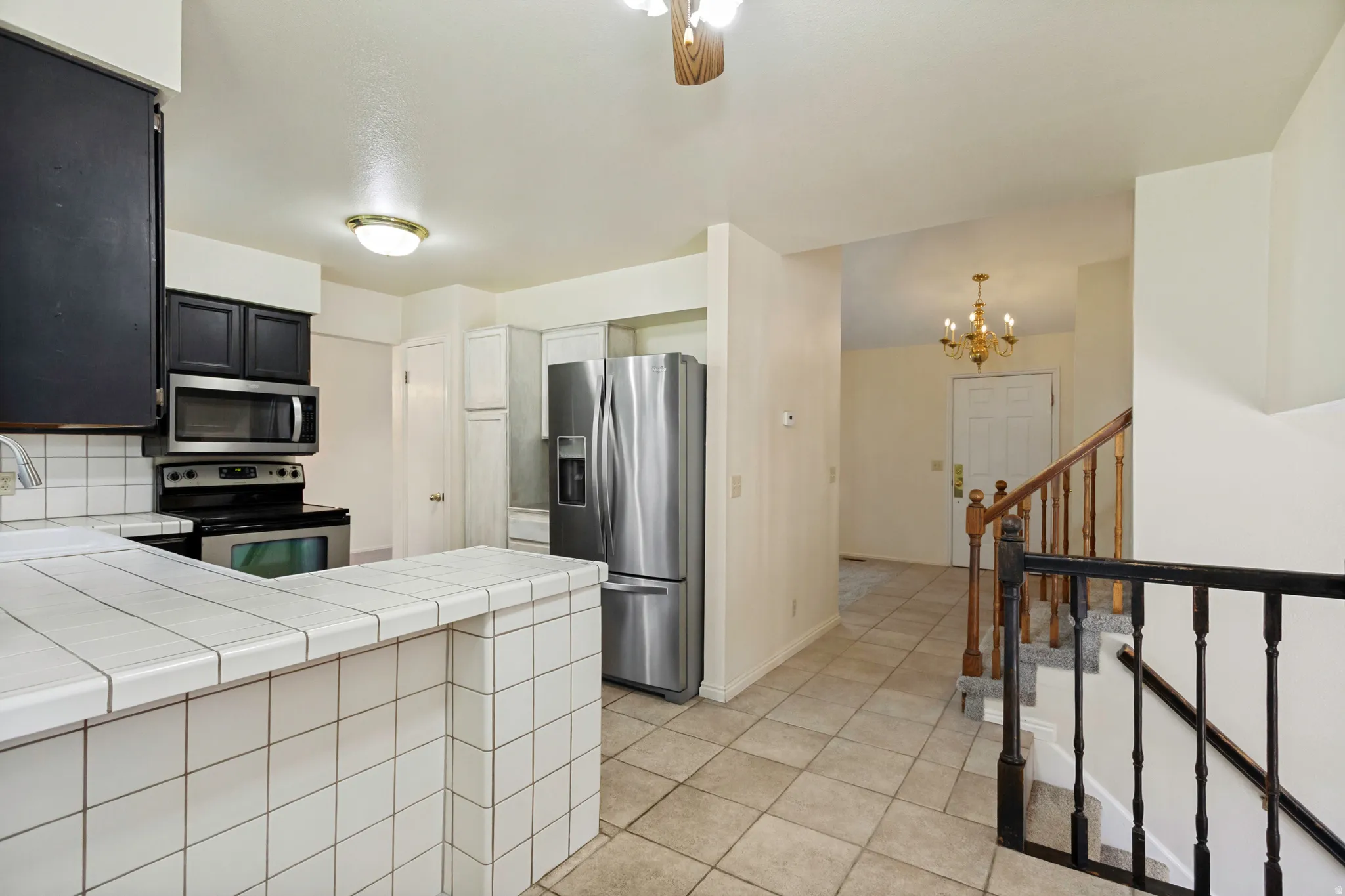 Kitchen featuring tile countertops, stainless steel appliances, and dark cabinetry