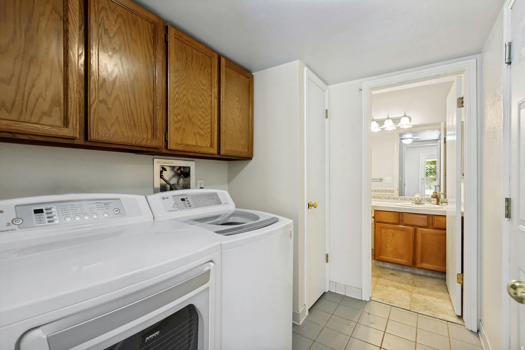 Laundry area featuring upper cabinetry, tile flooring, and a dedicated utility space