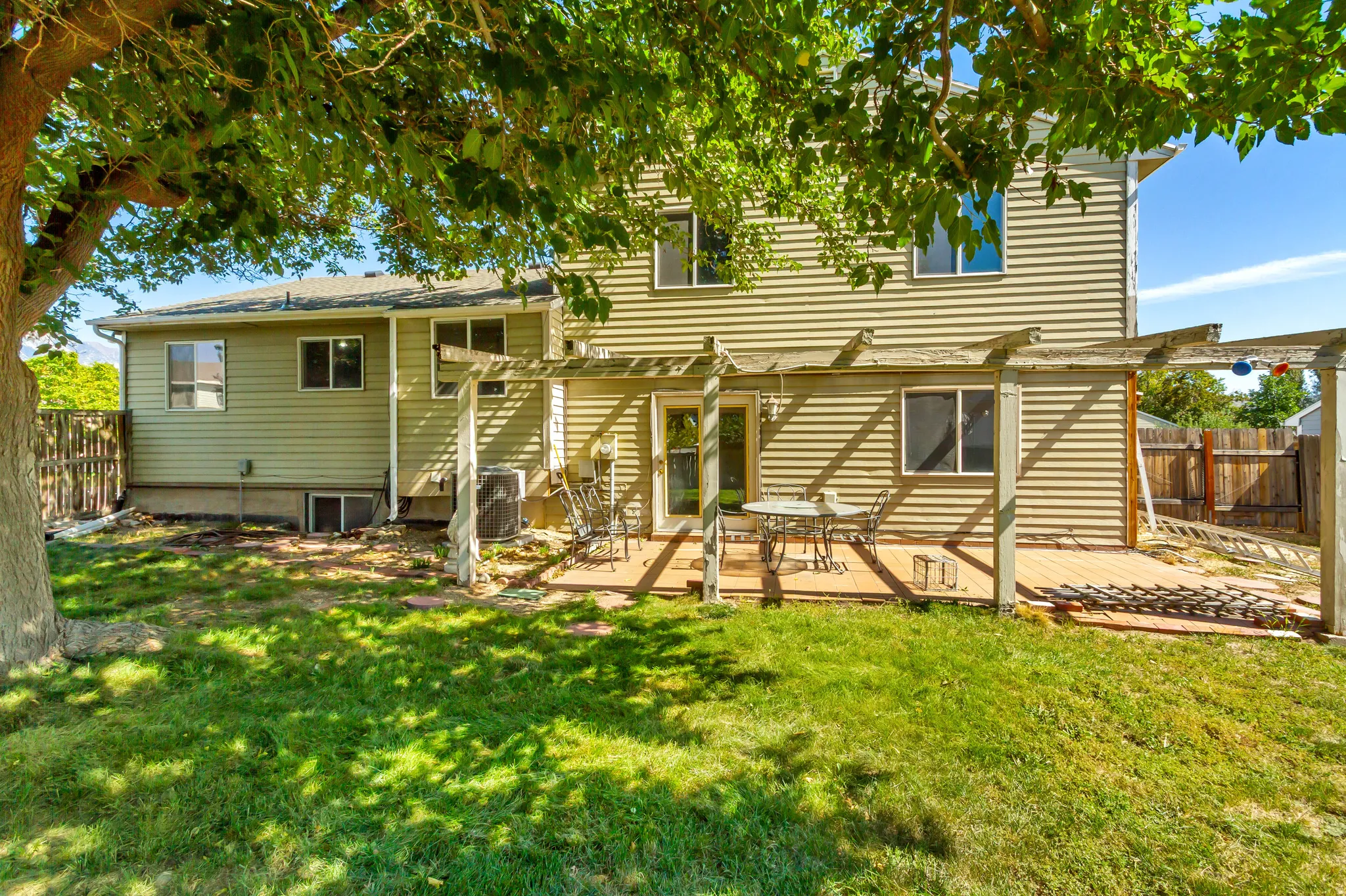 Back of property - Expansive backyard featuring a manicured lawn, a wooden deck, and a pergola structure