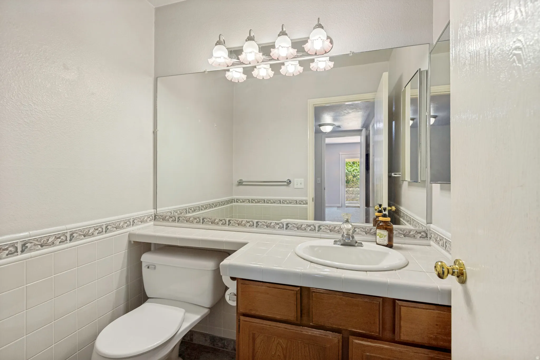 Bathroom vanity with integrated sink, wood-finish cabinetry, and a full-width mirror