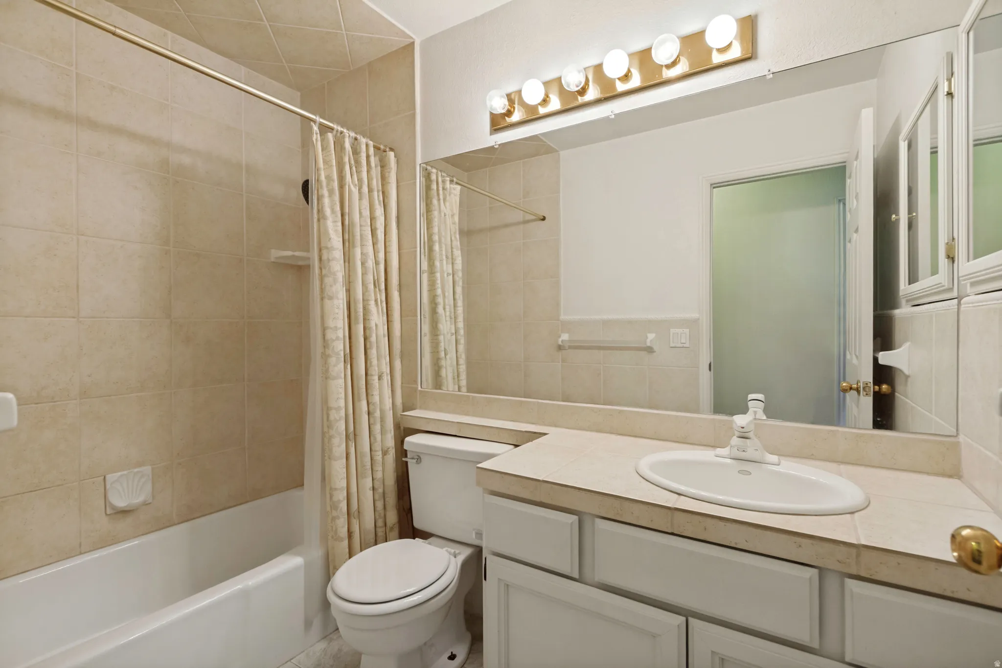 Secondary - Bathroom featuring a vanity with an integrated sink, built-in medicine cabinets, full-width mirror, and a tub with a tile surround