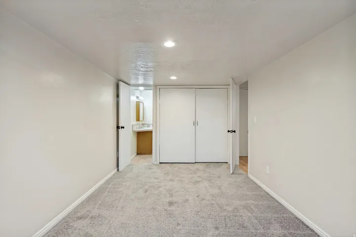 ADU - Recessed lighting, light gray carpet flooring, white walls, and white bi-fold closet doors